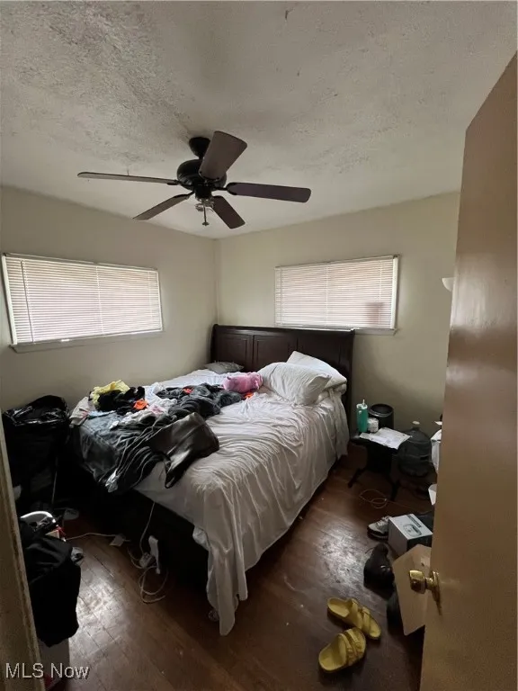 Bedroom with a textured ceiling, hardwood / wood-style flooring, and ceiling fan
