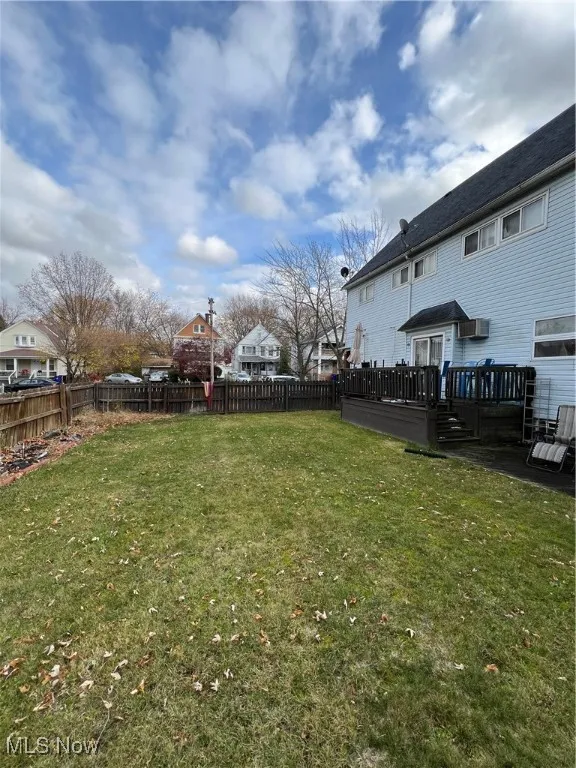 Fenced backyard with a deck, a residential view, and an AC wall unit