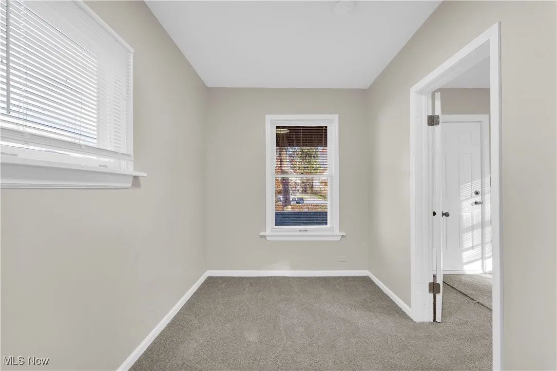 Carpeted spare room featuring baseboards