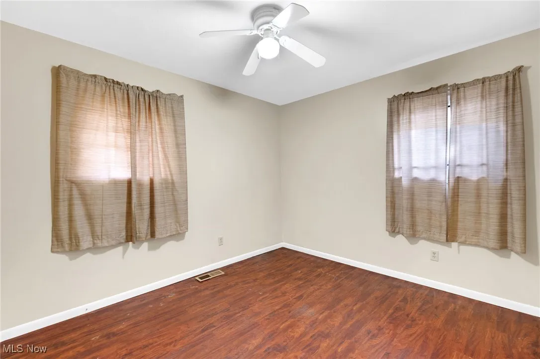 Spare room with dark wood finished floors and a ceiling fan