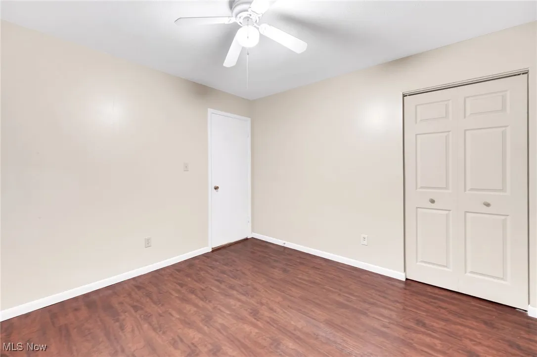Unfurnished bedroom with dark wood-style flooring, a closet, and ceiling fan