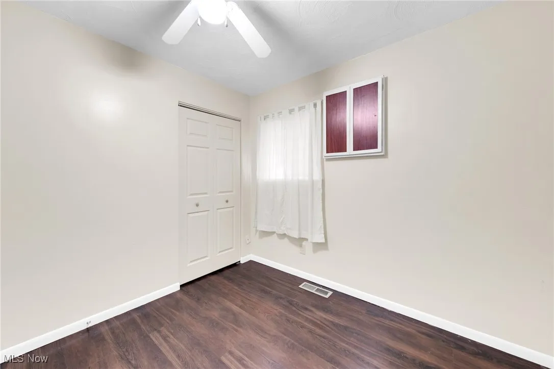 Unfurnished bedroom featuring a closet, dark wood-style flooring, and ceiling fan