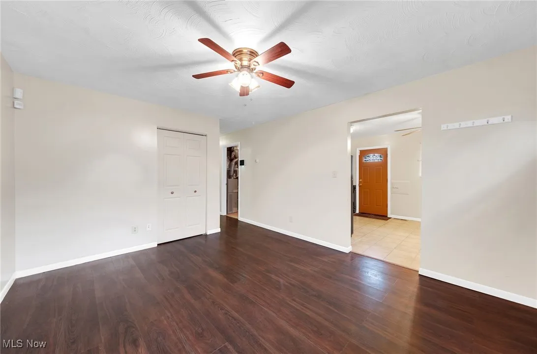 Unfurnished room featuring ceiling fan and dark wood-style floors