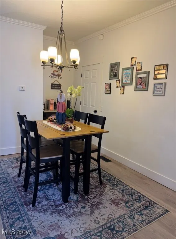 Dining area featuring crown molding, wood finished floors, and a chandelier