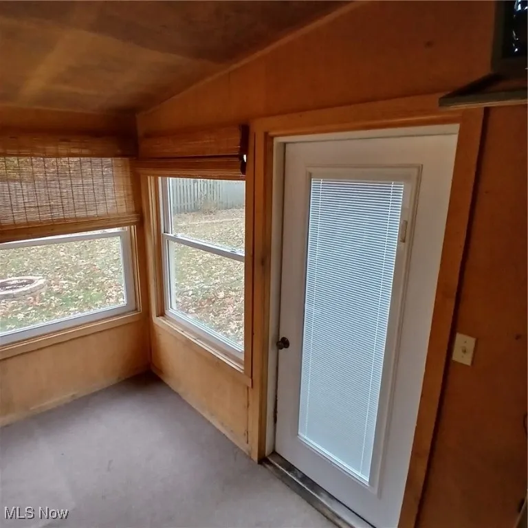 Doorway with vaulted ceiling and carpet