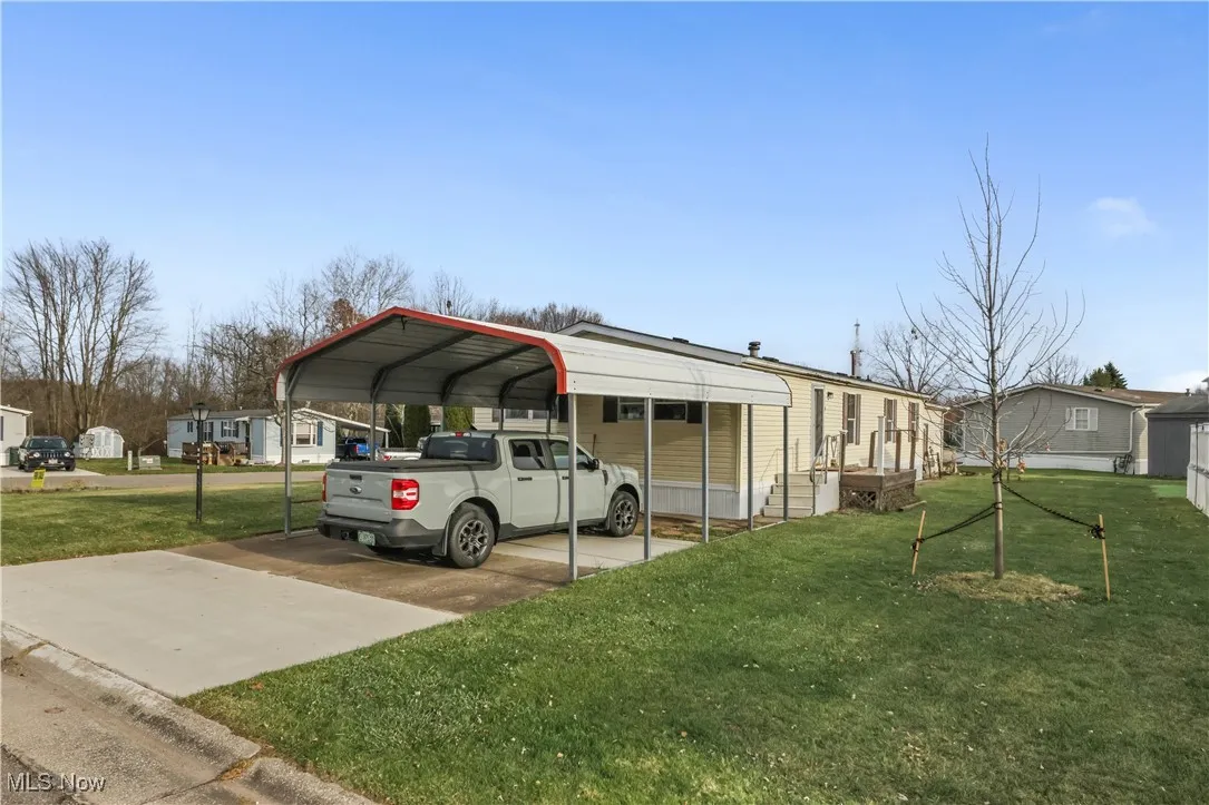 View of car parking featuring a detached carport, driveway, and a residential view