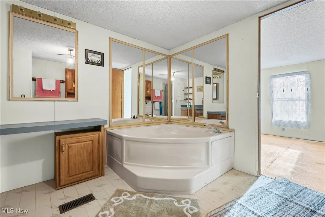 Bathroom featuring a textured ceiling, a bath, and vanity