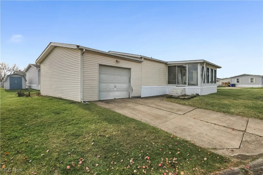 View of front facade with a sunroom, a front lawn, concrete driveway, and an attached garage