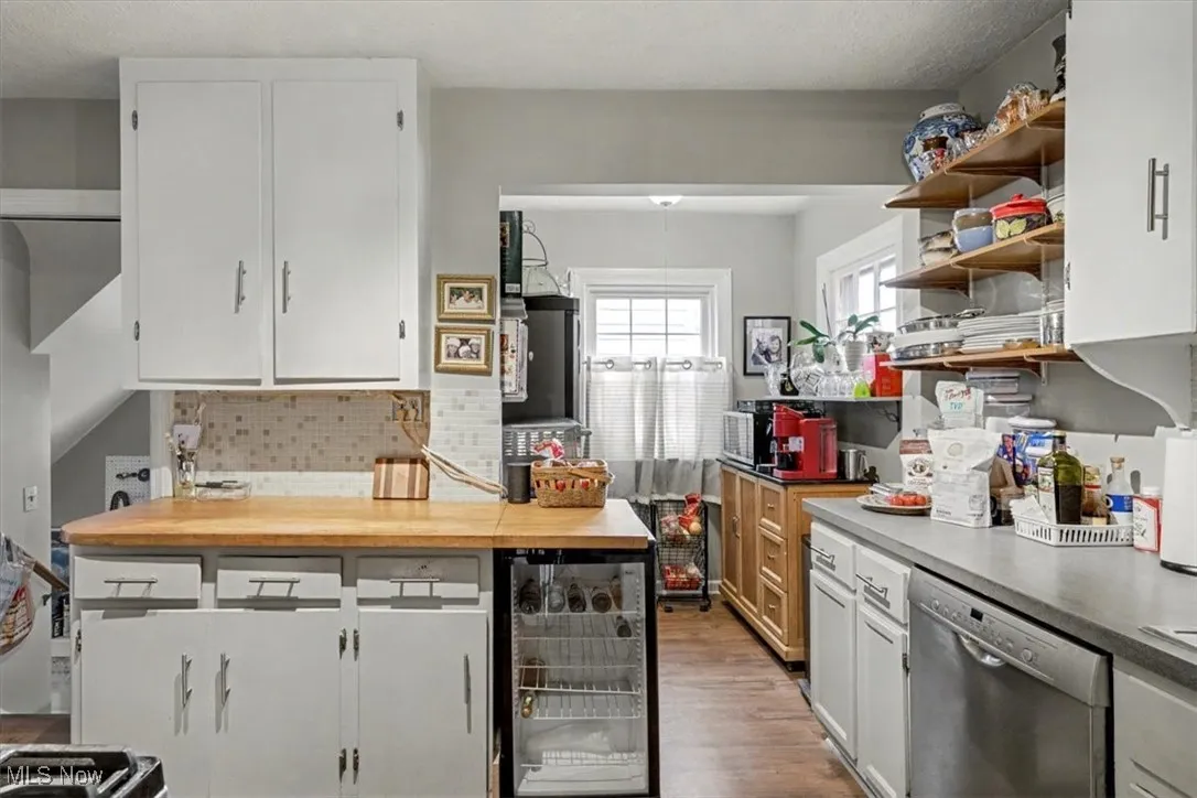 Kitchen with white cabinets, wooden counters, beverage cooler, open shelves, and a textured ceiling