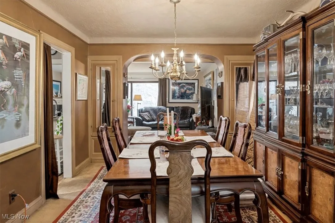 Dining space featuring a chandelier, arched walkways, and light colored carpet
