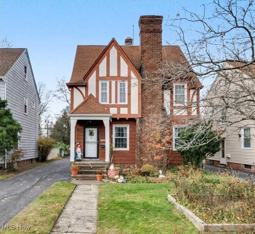 English style home featuring a chimney, a front lawn, asphalt driveway, a shingled roof, and stucco siding