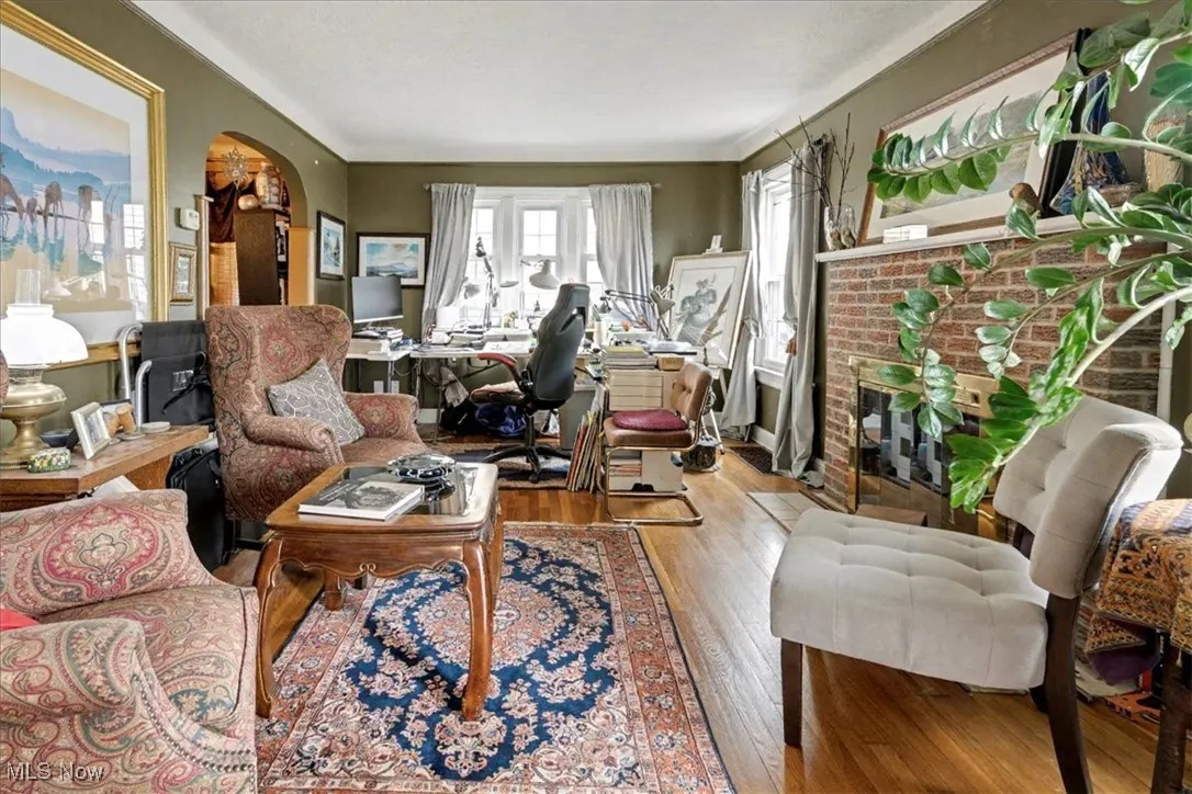 Living area with a fireplace, a desk, hardwood / wood-style flooring, and arched walkways