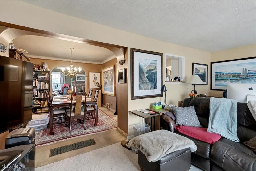 Living room with a chandelier, arched walkways, carpet, a textured ceiling, and crown molding