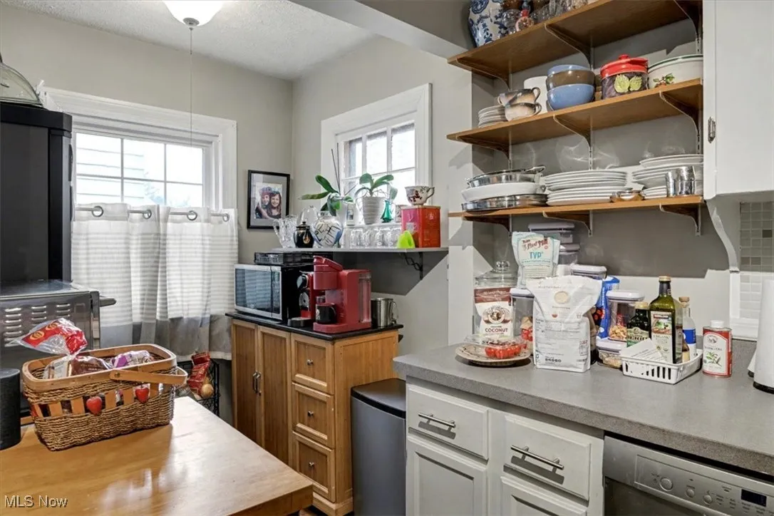 Kitchen with appliances with stainless steel finishes, light countertops, white cabinets, a textured ceiling, and dark countertops
