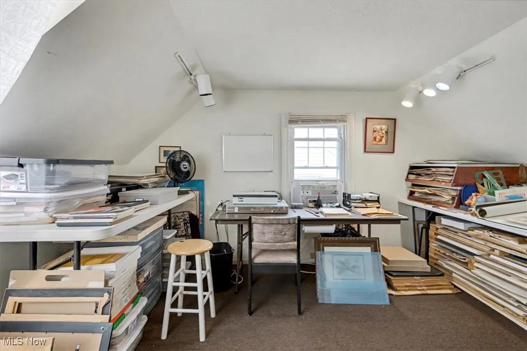 Carpeted office space with vaulted ceiling
