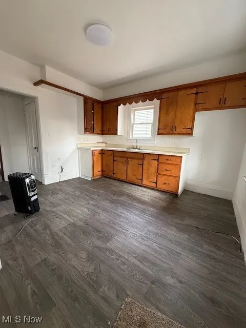 Kitchen featuring brown cabinetry, light countertops, and dark wood-style flooring