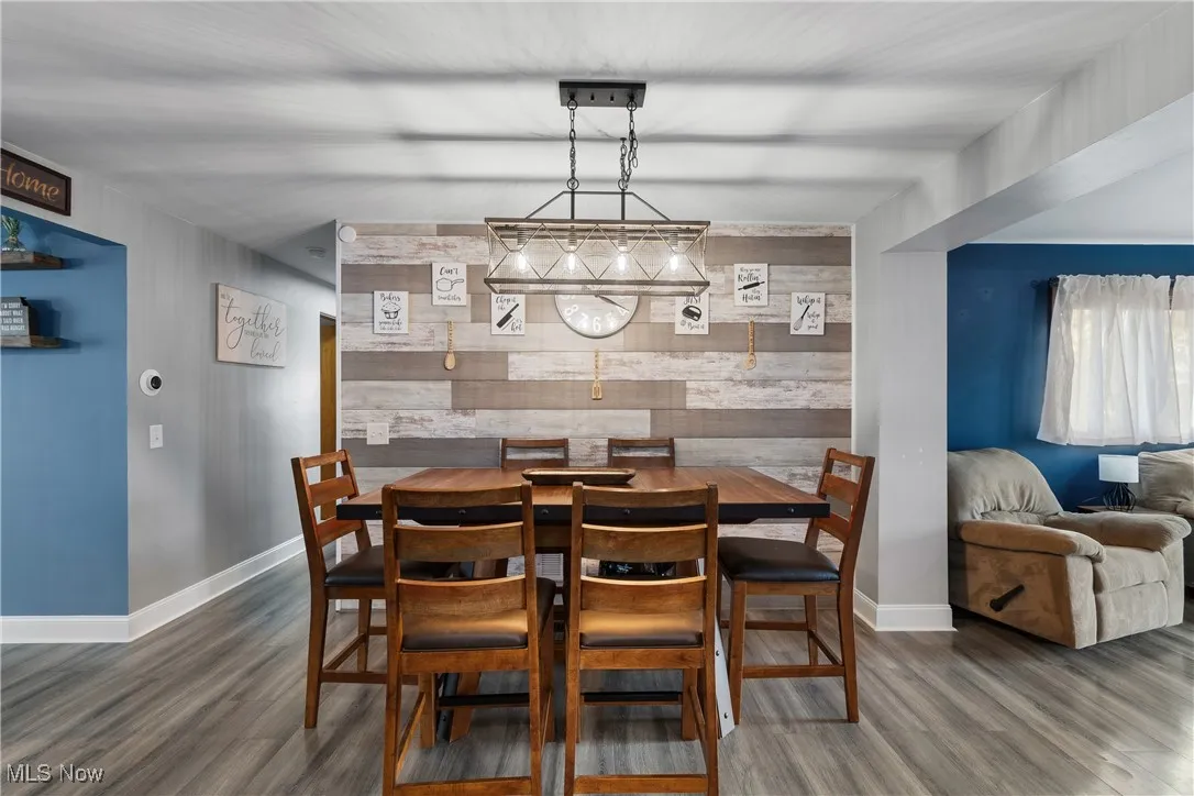 Dining room featuring an accent wall, wood walls, and dark wood-type flooring
