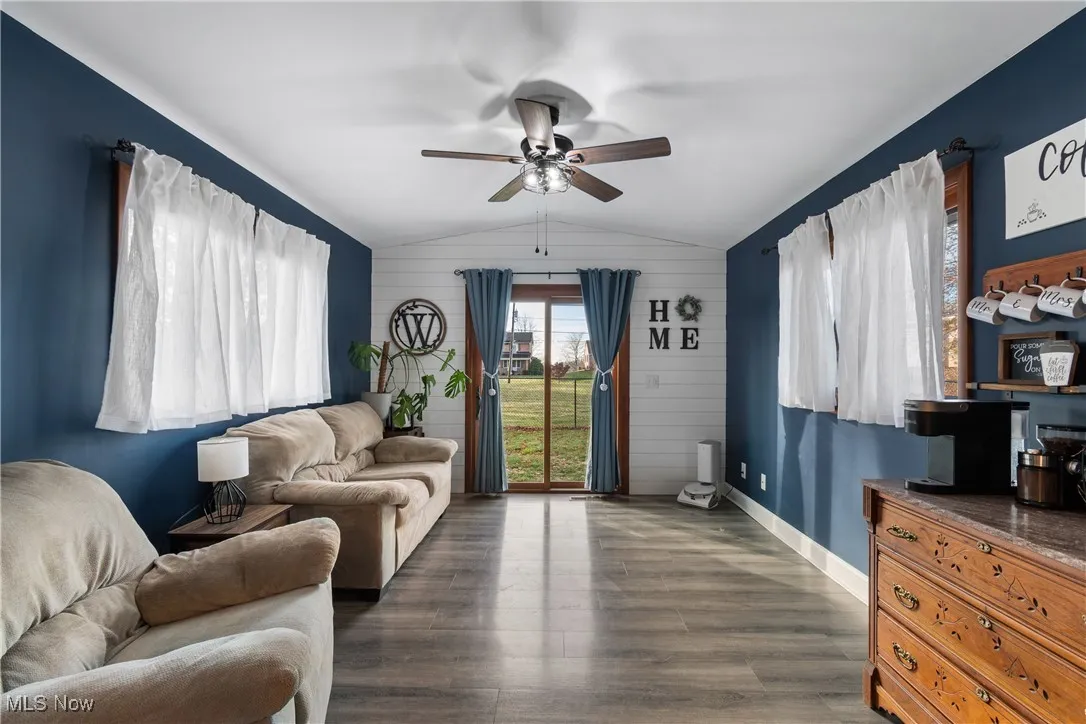 Living area featuring vaulted ceiling, dark wood finished floors, and ceiling fan