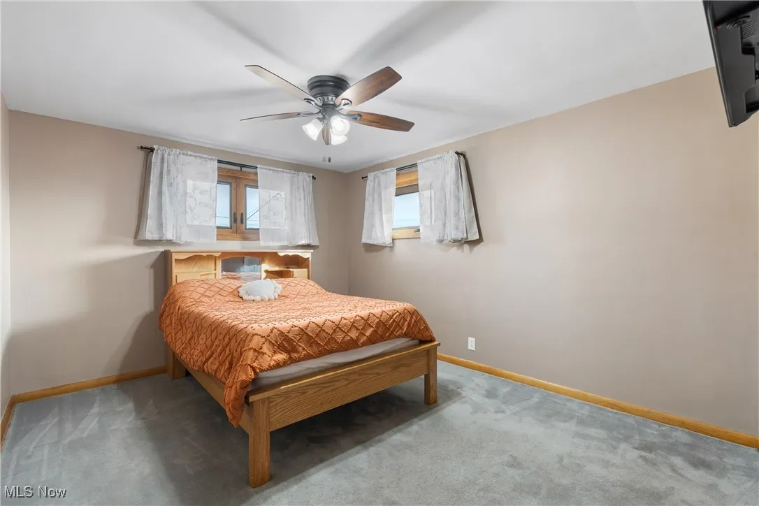 Carpeted bedroom with baseboards and ceiling fan