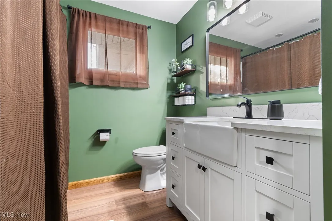 Full bath featuring vanity, curtained shower, and light wood finished floors