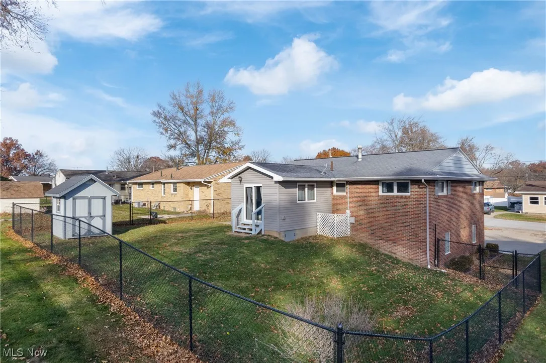 Rear view of property featuring a fenced backyard, a shed, brick siding, and entry steps