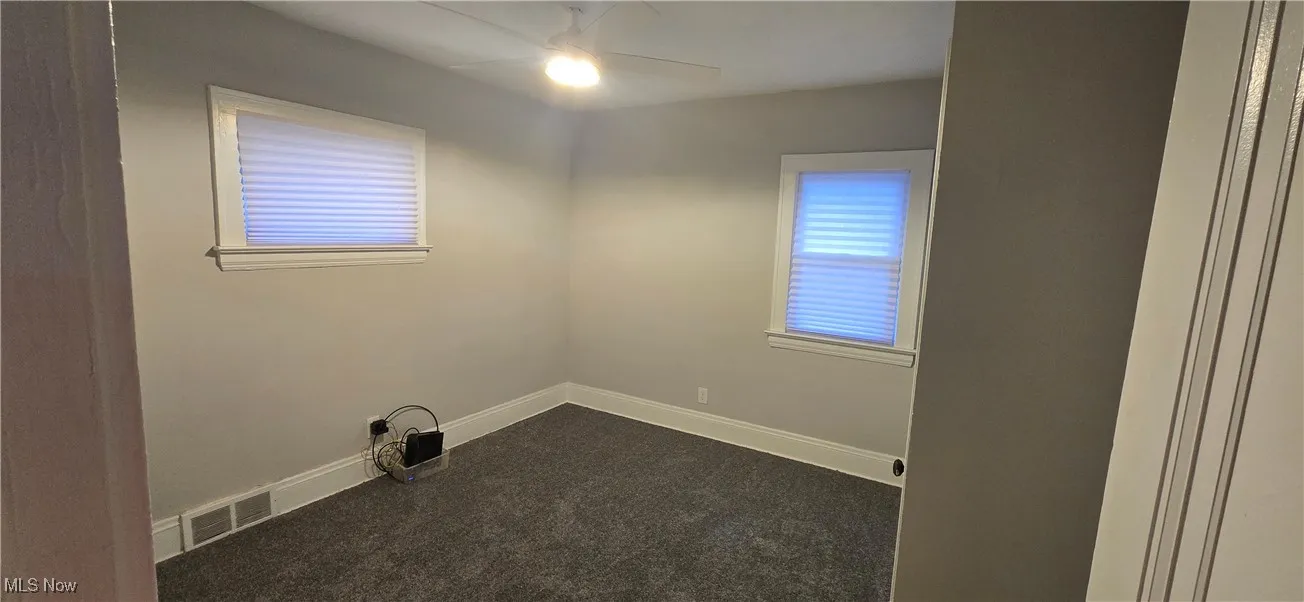 1st level bedroom 2 with dark carpet and ceiling fan