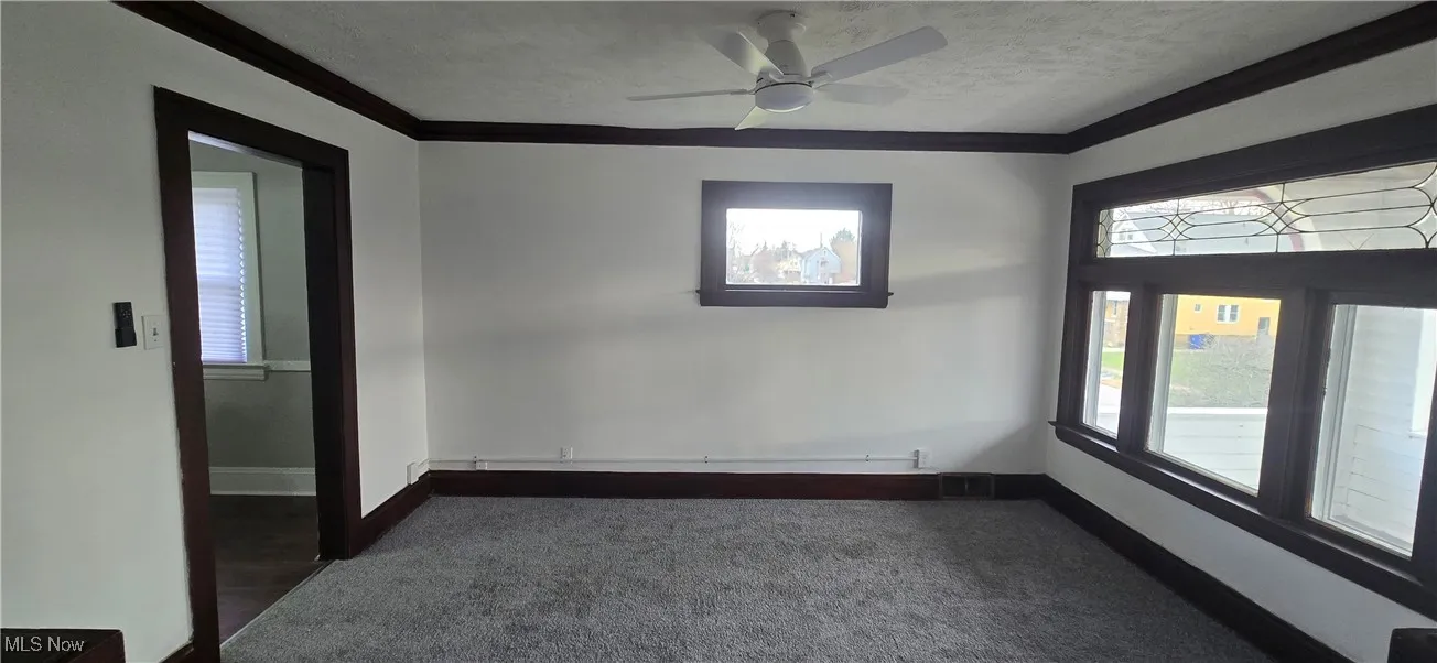 2nd level dining room with crown molding, dark colored carpet, ceiling fan, and a textured ceiling