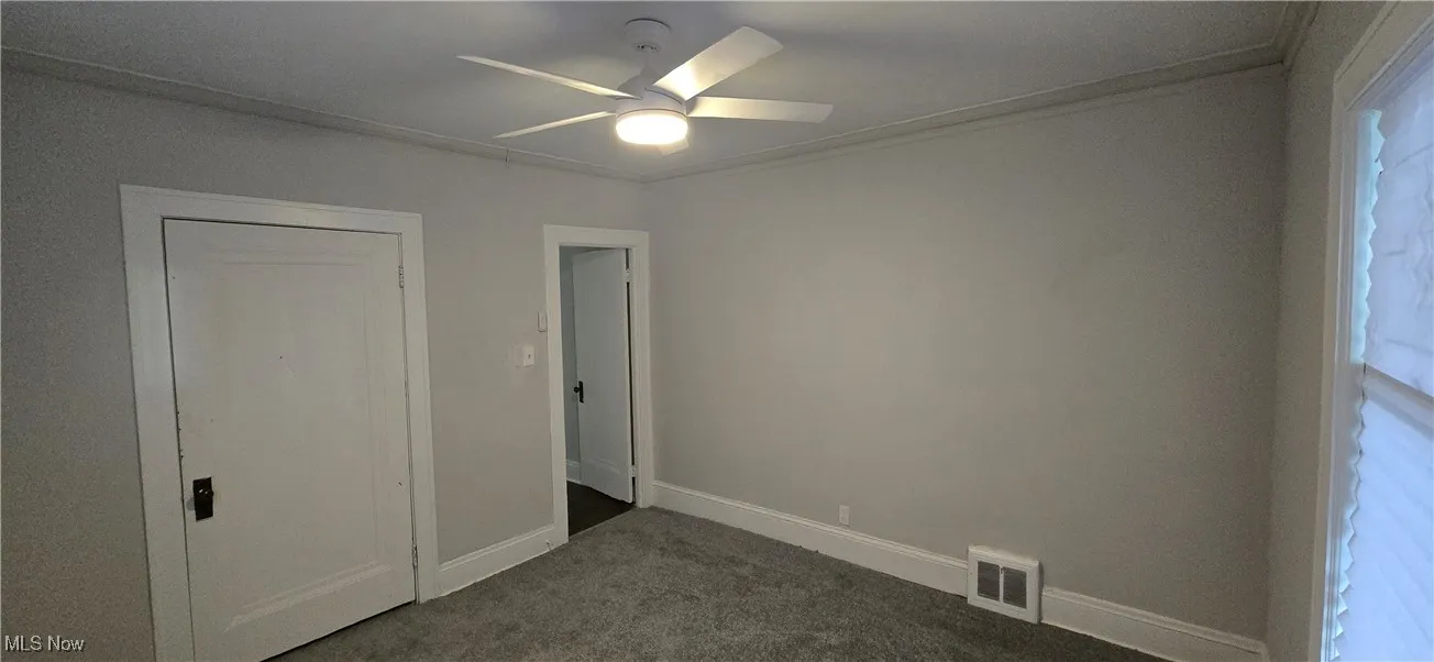 1st level bedroom 1 with carpet floors, ceiling fan, and ornamental molding