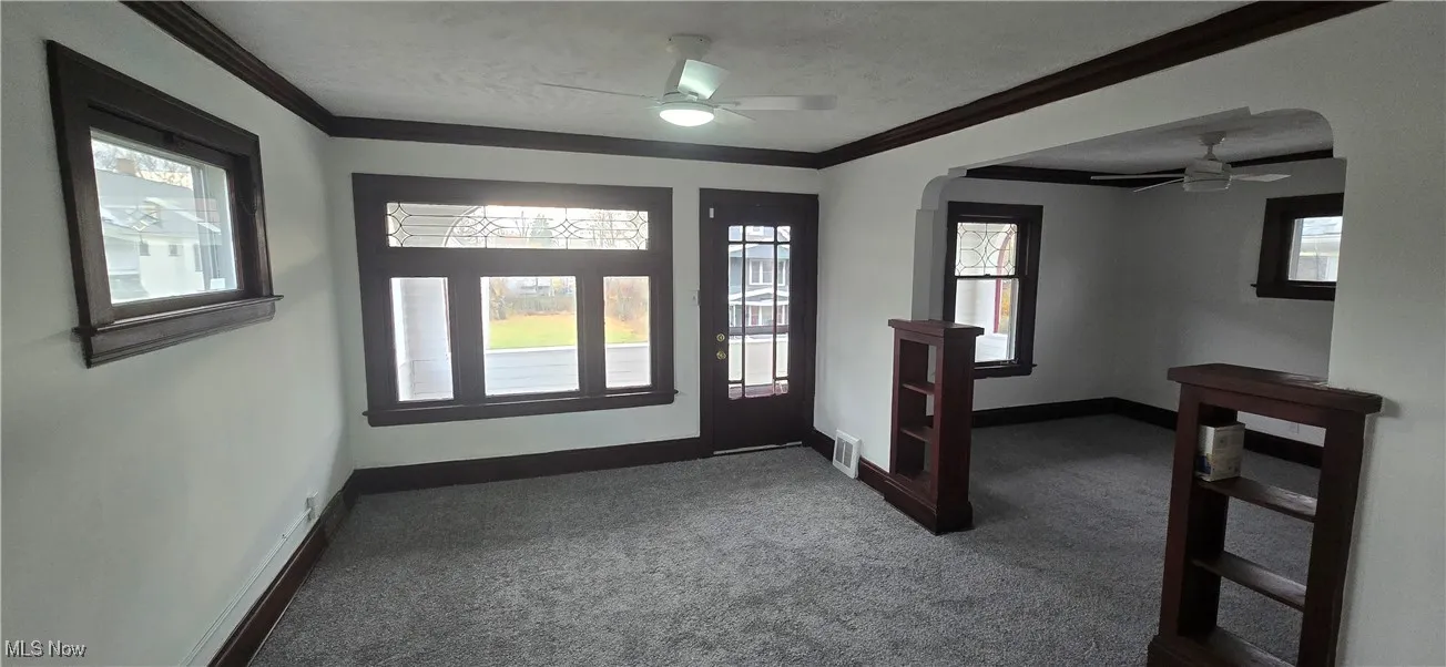 2nd level dining room with dark colored carpet, crown molding, ceiling fan, a textured ceiling, and arched walkways