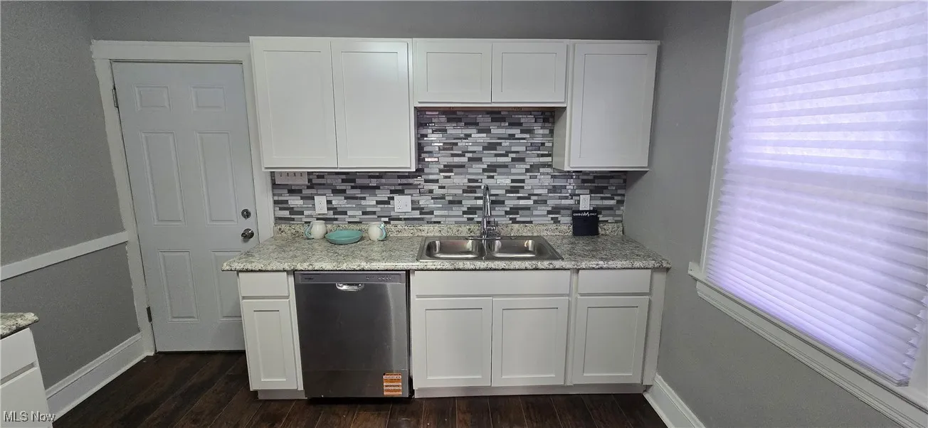 2nd level Kitchen featuring dishwasher, white cabinets, decorative backsplash, dark wood-type flooring, and light stone countertops
