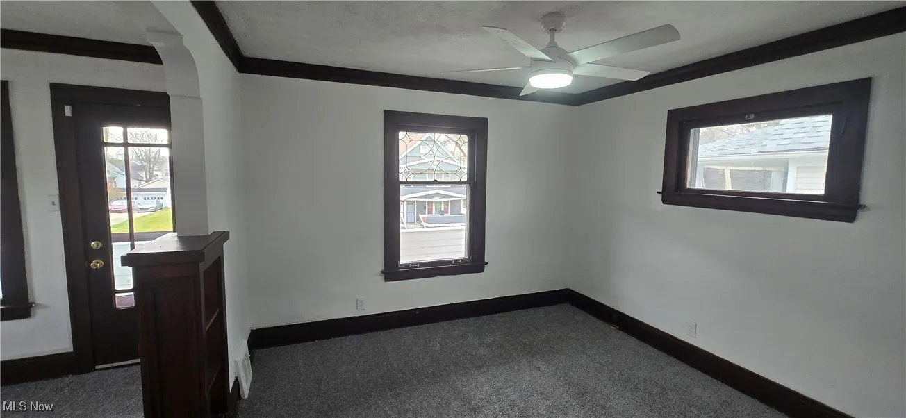 2nd level living room with dark colored carpet, crown molding, a ceiling fan, and plenty of natural light