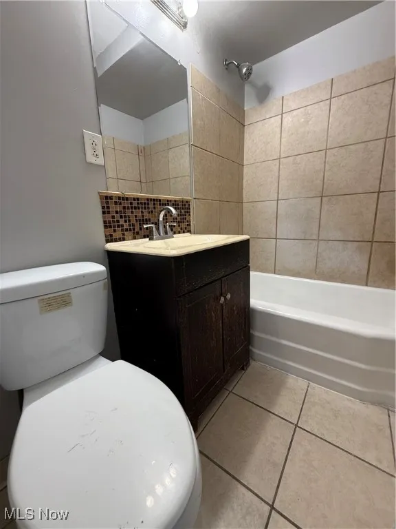 Bathroom with vanity, light tile patterned floors, backsplash, and  shower combination