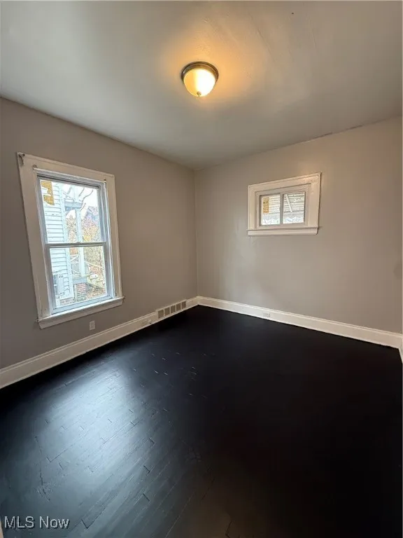 Spare room featuring baseboards and dark wood-style floors