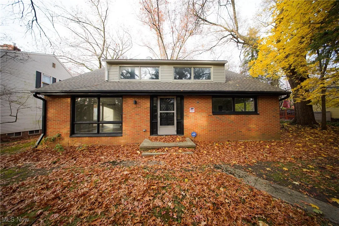 View of front of house with brick siding and roof with shingles