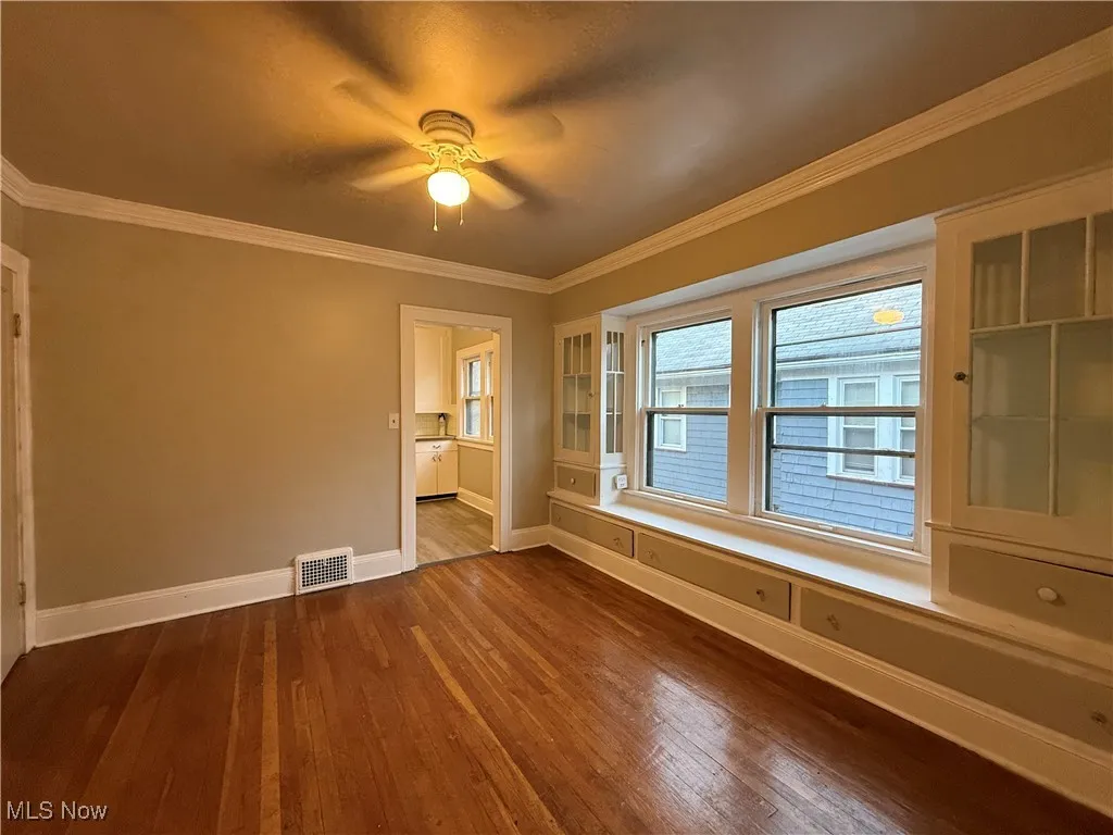 Spare room featuring ornamental molding, dark wood finished floors, and ceiling fan