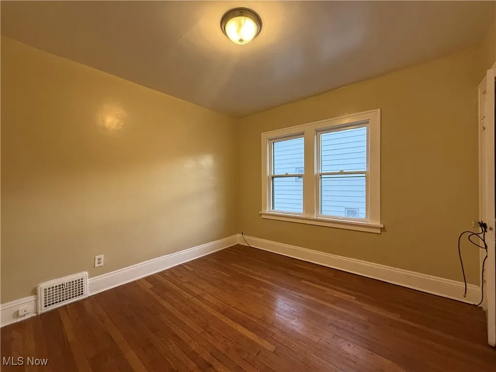Spare room featuring baseboards and dark wood finished floors