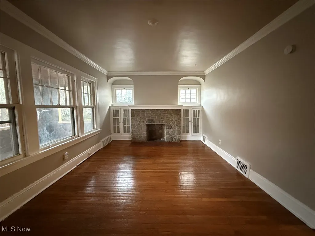 Unfurnished living room featuring a fireplace, dark wood-style floors, and crown molding