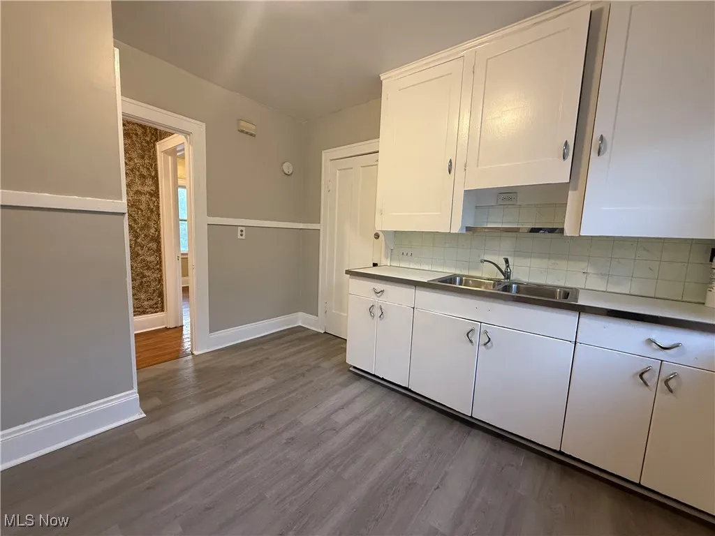 Kitchen featuring white cabinetry, tasteful backsplash, and dark wood-type flooring