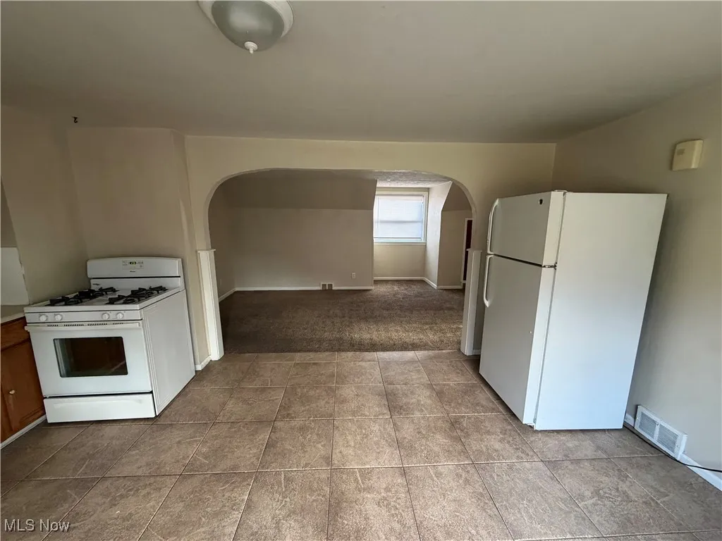 Kitchen featuring white appliances, arched walkways, and light countertops