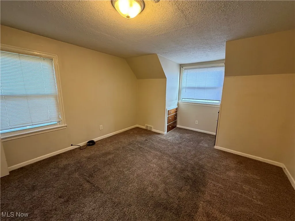bedroom with a textured ceiling and dark carpet