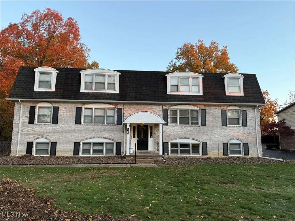 Split foyer home featuring a front yard, brick siding, and mansard roof