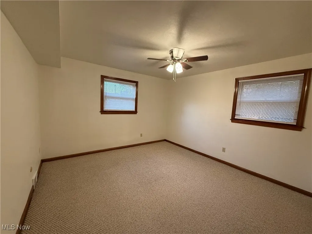 Spare room featuring carpet flooring and baseboards