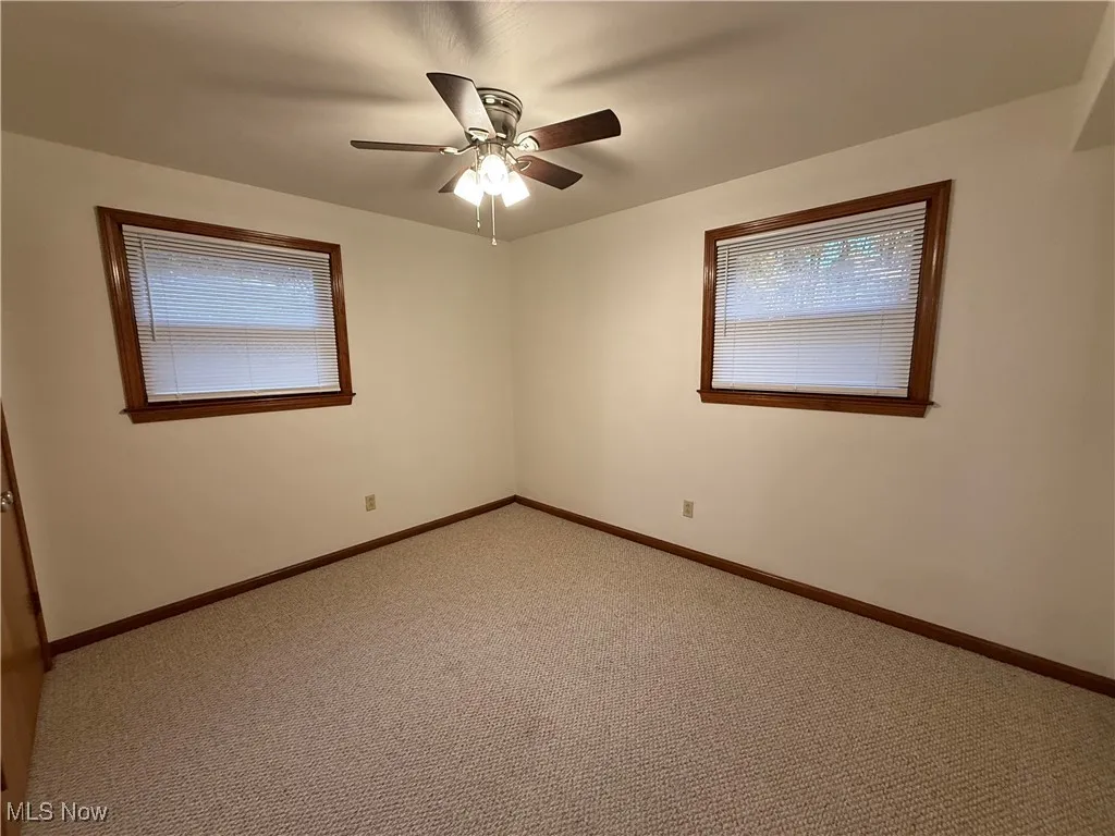 Empty room with carpet floors and a ceiling fan