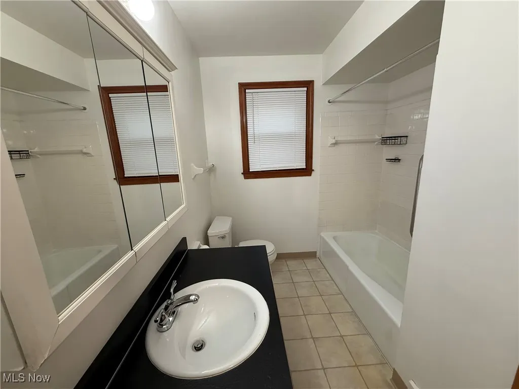 Bathroom with shower / washtub combination, light tile patterned floors, and vanity