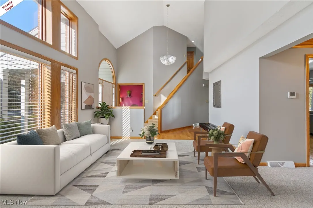 Living area with high vaulted ceiling, stairs, and a chandelier