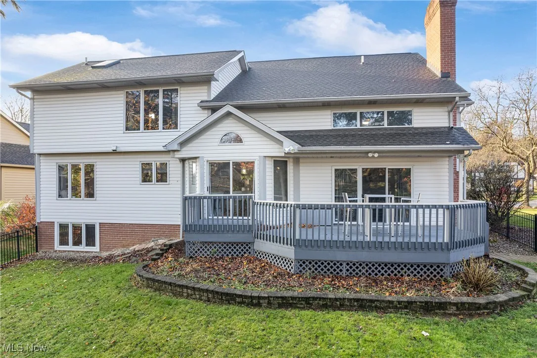 Back of property featuring a deck, a chimney, and a shingled roof