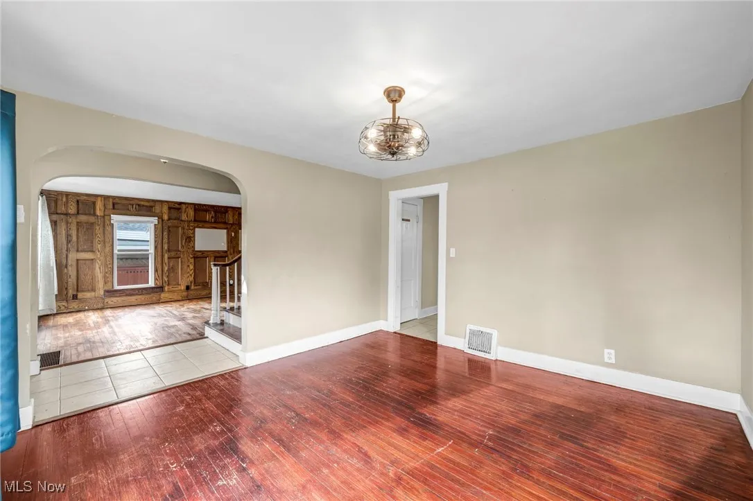 Spare room featuring stairway, hardwood / wood-style flooring, and arched walkways