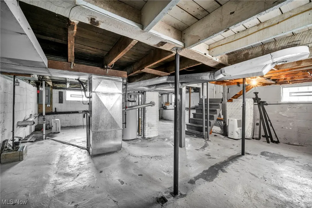 Below grade area with stairway, heating unit, water heater, and electric panel