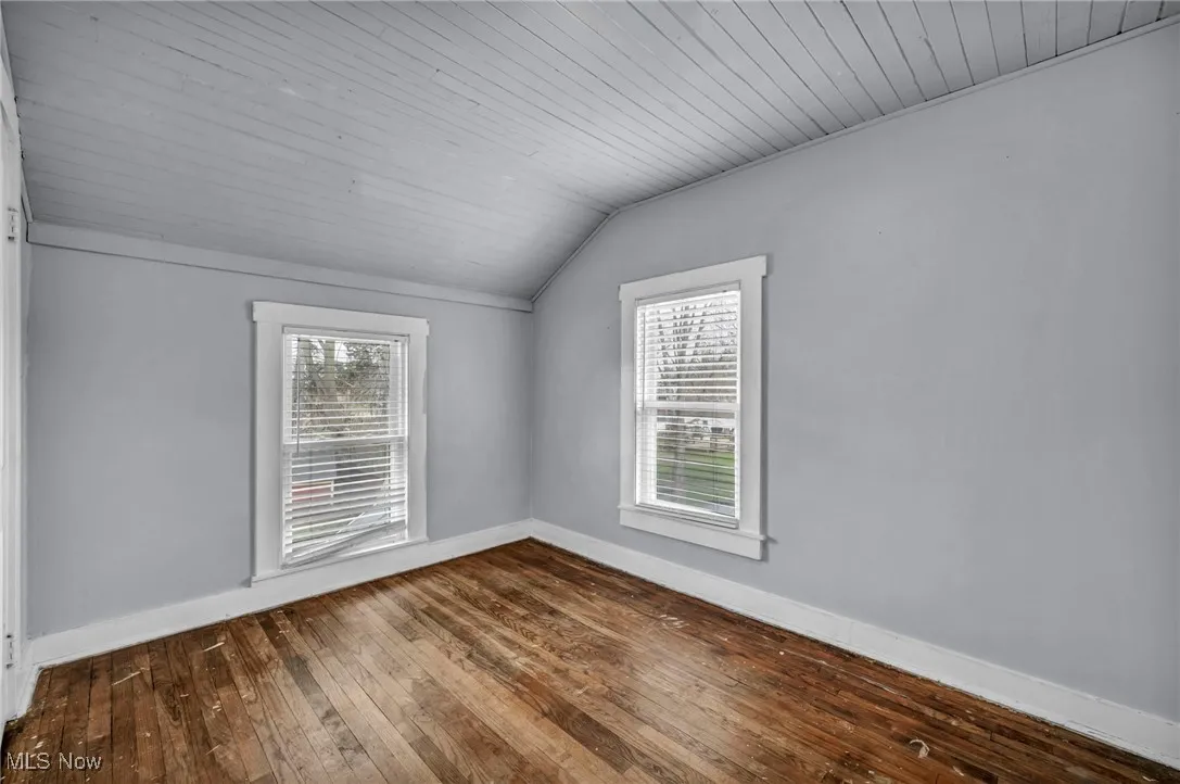 Additional living space with vaulted ceiling, wood ceiling, plenty of natural light, and dark wood-type flooring