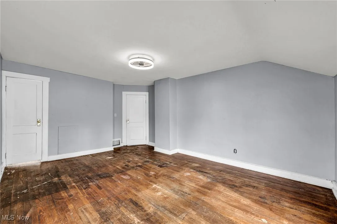 Unfurnished room with vaulted ceiling and dark wood-type flooring